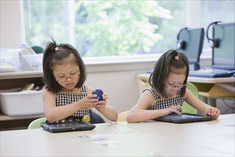 Mixed race Down syndrome students using tablet computers in classroom