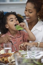 Young girl eating a leaf of lettuce at the dinner table
