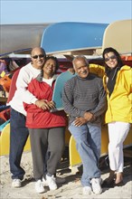 Two senior couples in front of canoes at beach