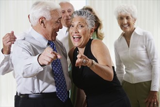 Senior couple at party pointing in surprise
