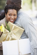 African couple holding gifts and hugging