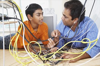 Middle Eastern father and son untangling wires