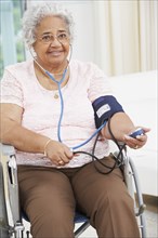 Senior African American woman taking own blood pressure