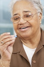 Senior African American woman looking at pill