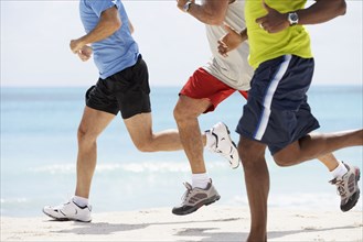 Multi-ethnic men running in beach