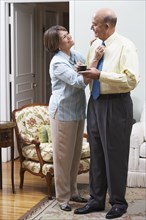 Senior Hispanic woman adjusting husband's necktie