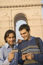 Indian friends with cell phone and credit card near the India Gate
