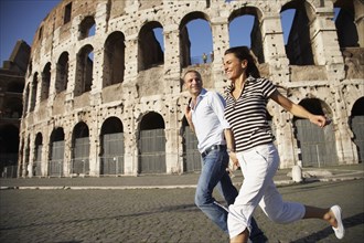 Tourist couple running near coliseum
