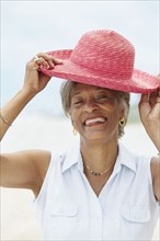 African woman putting on straw hat