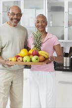 African couple holding tray of fruit