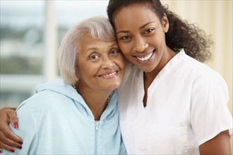 African American nurse hugging senior woman