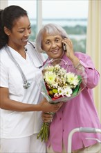 Nurse helping African American woman talking on cell phone