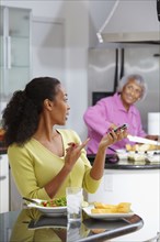 African American woman eating salad and talking on cell phone