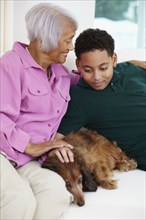 African American grandmother and grandson petting dog