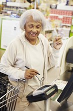 Senior African American woman paying with credit card in grocery store