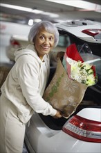 Senior African American woman putting groceries into trunk of car