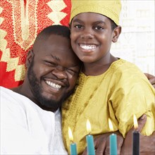 African American father hugging son in traditional clothing