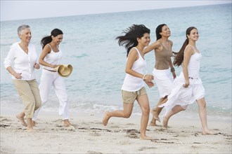 Diverse women running on beach together