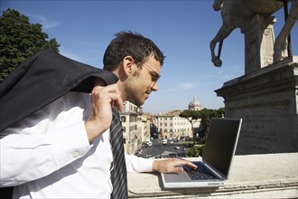 Italian businessman using laptop outdoors