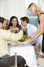 Woman serving friends salad at dinner party
