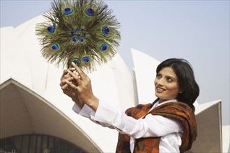 Mixed race woman holding peacock feather fan