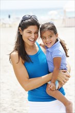 Hispanic mother and daughter enjoying beach