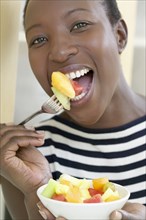 African American woman eating fruit salad