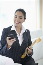 Hispanic businesswoman text messaging on cell phone