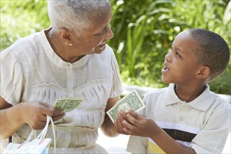 African American grandmother handing money to grandson
