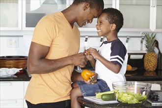 African American father and son making salad in kitchen