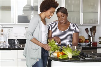 African American mother and daughter preparing salad