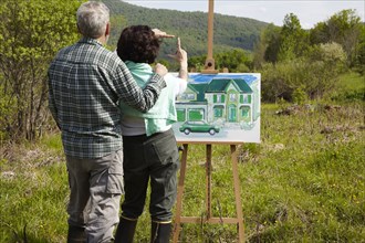 Caucasian couple visualizing house in rural landscape