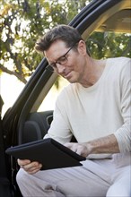 Caucasian man using digital tablet in car