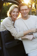 Caucasian couple smiling by car