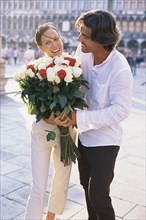 Man giving girlfriend flowers on city street