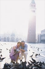 Senior couple feeding pigeons in St. Mark's Square
