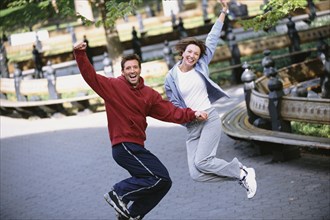 Couple jumping for joy in urban park