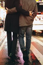 Couple walking on city street lit up at night