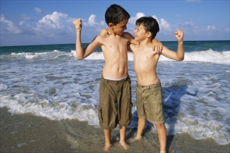 Boys flexing their muscles on beach