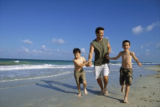 Father and sons walking together on beach