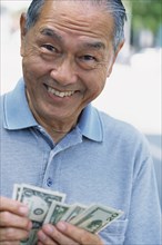 Senior man counting money outdoors