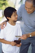 Senior man giving grandson credit card