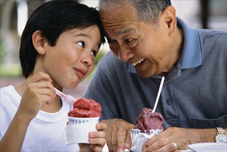 Senior man and grandson eating ice cream outdoors