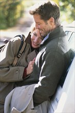 Couple hugging by car