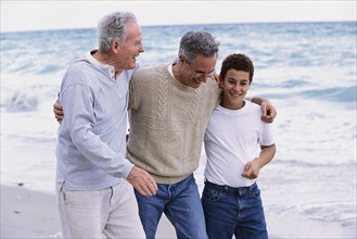Three generations of Caucasian men walking on beach