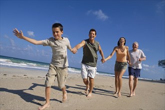 Caucasian family holding hands on beach