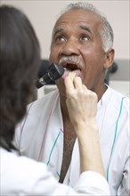 Doctor checking Senior man's tongue