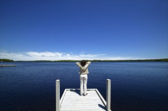 Woman overlooking lake on wooden dock