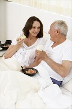Senior couple eating breakfast in bed