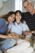 Hispanic family smiling together on sofa